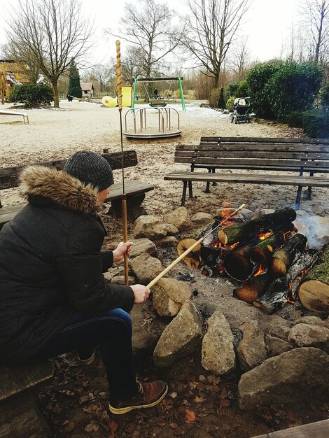 A person using a pitchfork to turn a compost pile in a backyard garden. The compost is steaming slightly, indicating active decomposition.