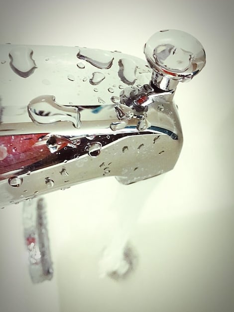 A close-up photo of a dripping faucet with a wrench beside it, focusing on the need for quick repairs to prevent water wastage.
