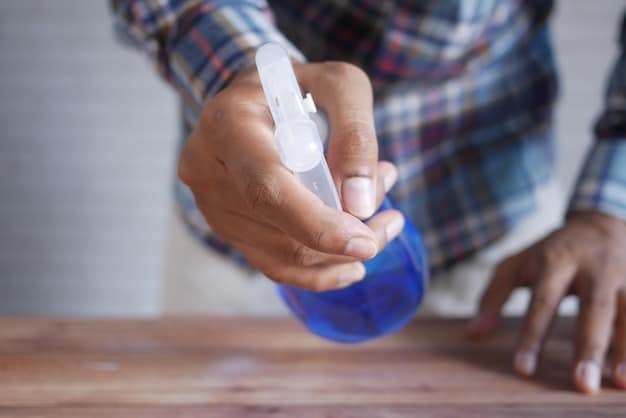 A close-up shot of a hand using a spray bottle filled with a homemade cleaning solution on a kitchen counter. The solution is labeled with natural ingredients like vinegar and essential oils.