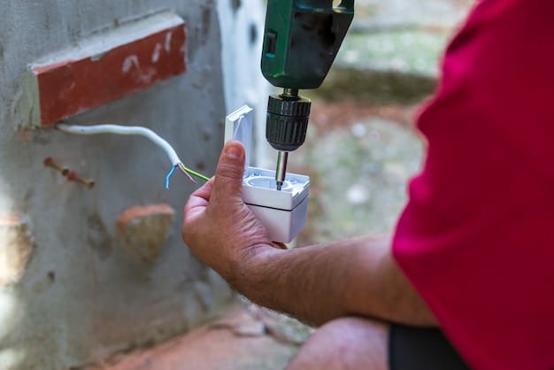 A certified electrician working on the installation of a home battery storage system, connecting wires to the inverter with safety equipment in use.