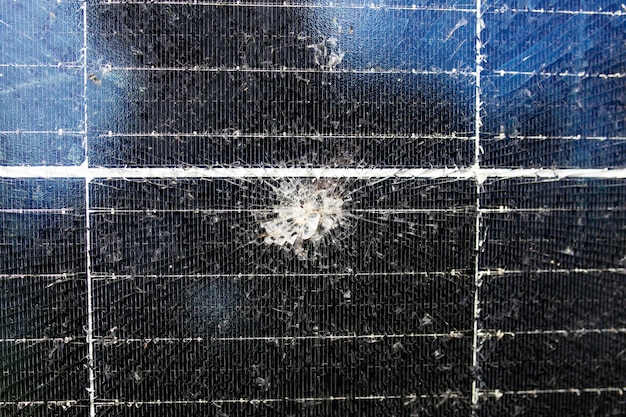 A close-up of a solar panel with visible cracks and damage from hail, demonstrating the physical damage extreme weather can cause.