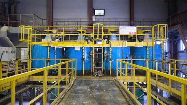Inside a chemical recycling facility, showcasing the machinery and processes involved in breaking down the composite materials of wind turbine blades, with workers in protective gear overseeing the operation.