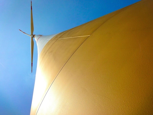 A close-up shot of a wind turbine blade spinning in a wind farm at sunset, showcasing the technology's ability to generate clean power from wind energy.