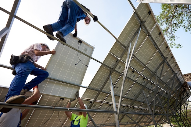 A diverse group of workers installing solar panels on the roof of a commercial building in a sunny urban setting, highlighting the job creation aspect of the renewable energy industry.