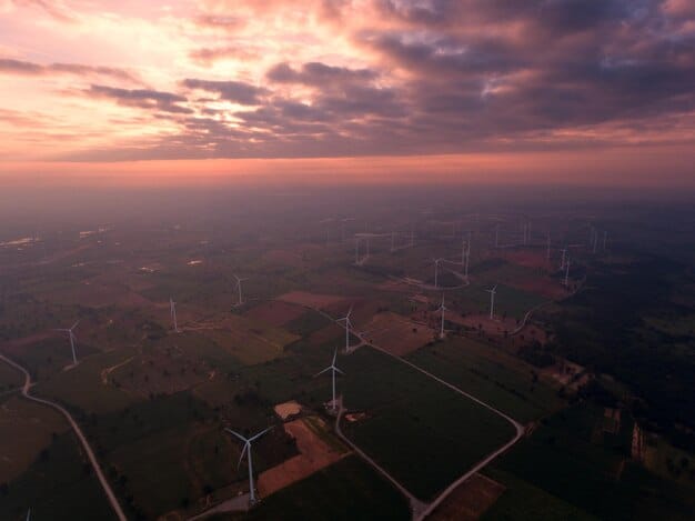 An aerial view of a modern wind farm at sunset, with a smart grid control center visible in the background, illustrating the infrastructure needed for renewable energy integration.