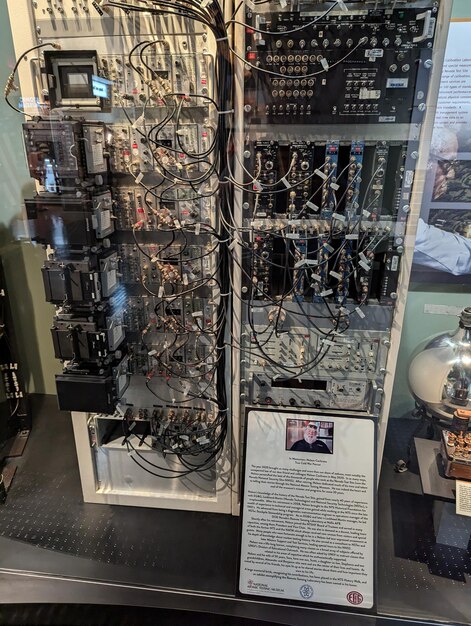 A detailed close-up of a US electrical grid control center. Multiple screens display real-time data of energy flow, with various colors representing different sources of energy (solar, wind, hydro, etc.). Technicians in the foreground are actively monitoring the system.