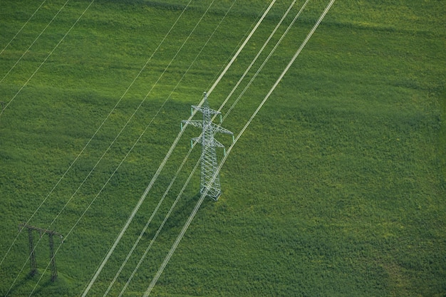 An aerial view of a newly constructed high-voltage transmission line stretching across a rural landscape. In the background, solar panel farms and wind turbine arrays are visible, illustrating the connection between renewable energy sources and grid infrastructure.