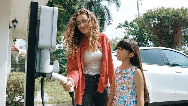 A family standing next to their new electric vehicle outside their house, with a charging station installed, showcasing the benefits of EV tax credits.