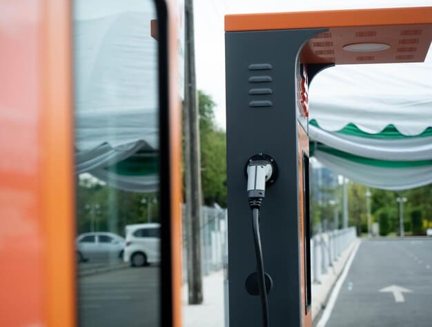 A close-up shot of a modern DC fast charging station along a highway rest stop. The station features a digital display showing real-time charging status and payment options. An electric SUV is plugged in, and the background shows other EV charging stations and a well-maintained rest area with green landscaping.
