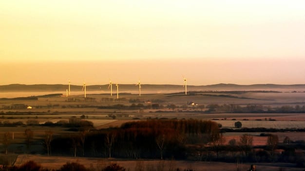 An aerial view of wind turbines in a field during sunset, with a focus on sustainability and renewable energy sources.