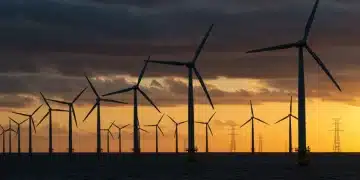 Offshore wind farm with interconnected turbines and grid infrastructure at sunset.