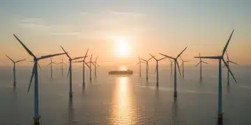 Offshore wind farm with turbines at sunrise over the ocean, symbolizing renewable energy and maritime industry.